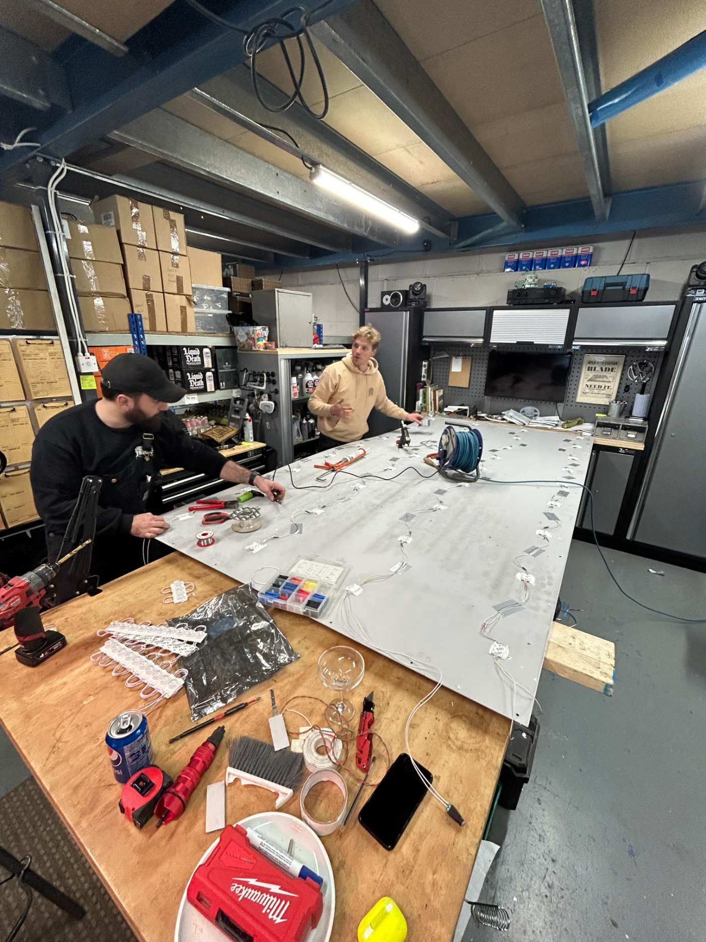 Two Beetle Juice makers wiring an LED sign panel on the workshop bench